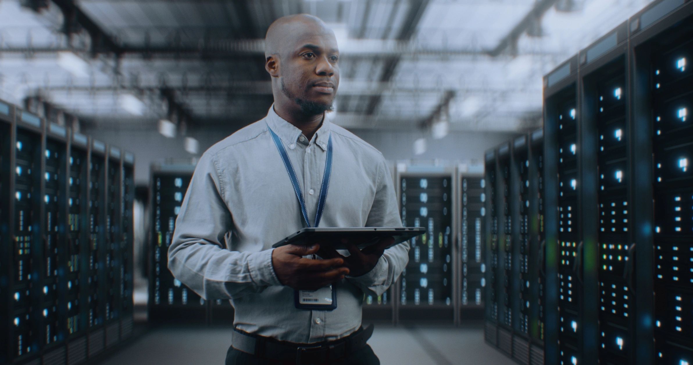 Network specialist using a tablet beside data centre server racks